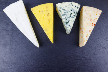 Set of various types of cheese on black slate background. Top view