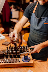 jewelry craftsman selecting a tool from his workbench in his workshop- arts, crafts and small businesses.