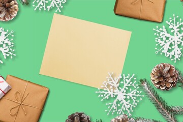Christmas blank greeting card mock-up scene. Festive winter composition. Craft envelope, pine cone, gift box and fir tree branch