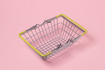 Metal shopping basket on a pink background. Toy shopping basket. Supermarket shopping concept.
