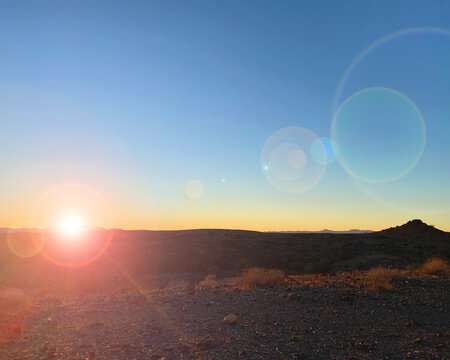 old west sunset lens flair setting sun over desert mountains