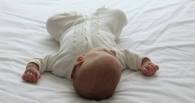 Overhead View Of Peaceful Sweet Little Infant Sleep On White Bedsheets In Comfy Pose Outstretch Arms Legs. Calm Healthy Small Baby Child In Cotton Sleeper Relax Lying On Back On Bed Take Daytime Nap