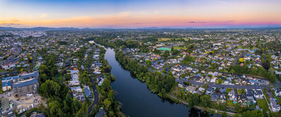 Aerial drone panoramic view at sunset, looking North down the Waikato River, over the city of...