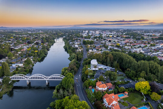 Aerial drone view at sunset, looking up the Waikato River towards the CBD, over the city of Hamilton (Kirikiriroa) in the Waikato region of New Zealand.