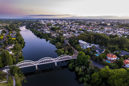 Aerial drone view at sunset, looking up the Waikato River towards the CBD, over the city of Hamilton (Kirikiriroa) in the Waikato region of New Zealand.