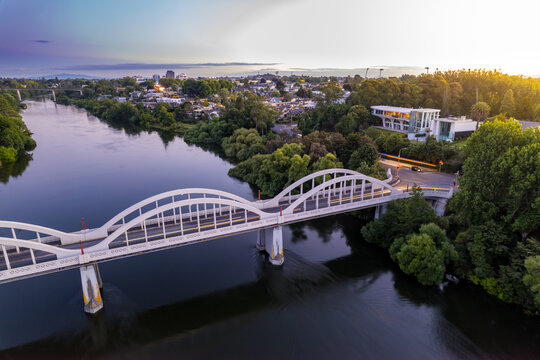 Aerial drone view at sunset, looking up the Waikato River towards the CBD, over the city of Hamilton (Kirikiriroa) in the Waikato region of New Zealand.