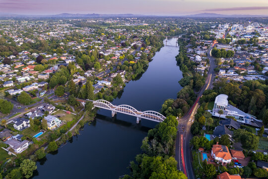 Aerial drone view at sunset, looking up the Waikato River towards the CBD, over the city of Hamilton (Kirikiriroa) in the Waikato region of New Zealand.