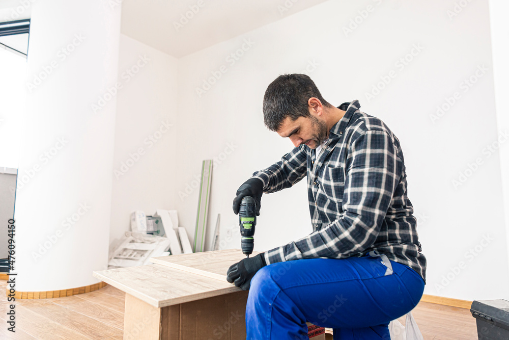 Wall mural The carpenter finalizing the assembly of the kitchen shelf