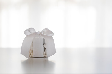 Confezione di confetti bianchi con nastro bianco su tavolo
