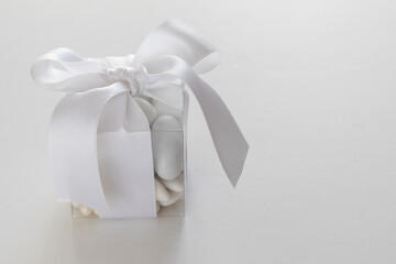 Confezione di confetti bianchi con nastro bianco su tavolo