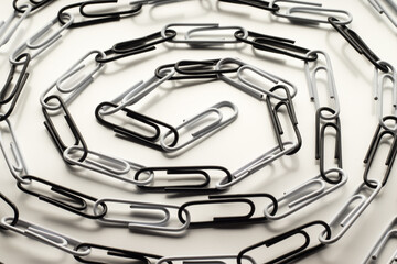 Spiral made of linked black and white paper clips on white background. Contrast, opposites, concept. Selective focus