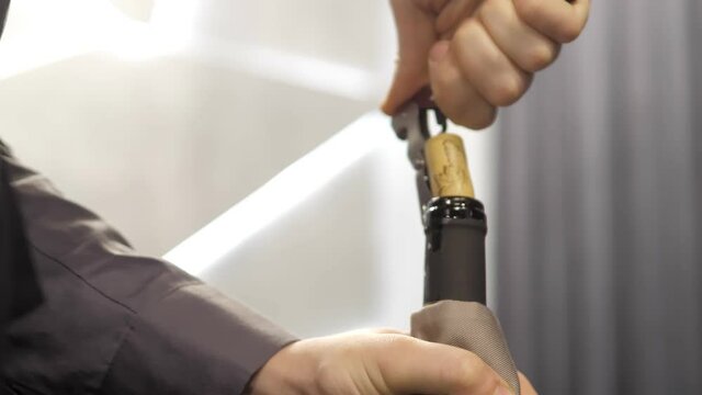A close-up of a corkscrew twisting into a bottle of red wine. A waiter opens a bottle of red wine with a real cork in an elite restaurant. A man is opening a bottle of vine.