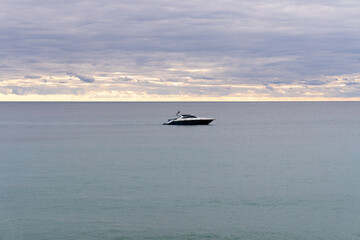 Obraz premium Seascape with a yacht in the calm sea, on a cloudy day.