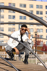 black man with sunglasses squatting posing on a bridge