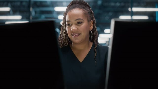 Portrait of African American Female IT Specialist Working on Desktop in Data Center. System Administrator Works on Web Services, Cloud Computing, Server Analytics, Cyber Security Maintenance, SAAS