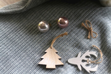 Wooden Christmas ornaments, small shiny baubles and gray sweater. Selective focus. 