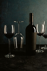 Compositionwith bottle of red wine and glasses of wine on dark background on the table in vintage style..