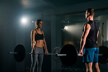 Fototapeta na wymiar A young woman and man training together in the gym