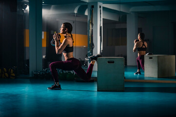A young fit woman doing split squats exercise in gym