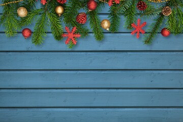 Fototapeta na wymiar Fir branch with Christmas decoration on a painted wooden background.