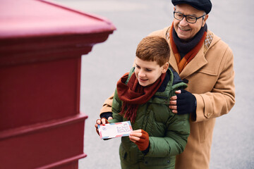 Happy little boy with grandfather sending a letter to Santa Claus.