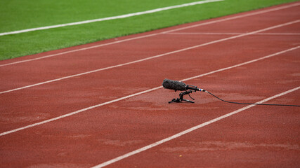recording microphone cannon standing on a tripod with a fluffy windscreen on a soccer field on an orange treadmill