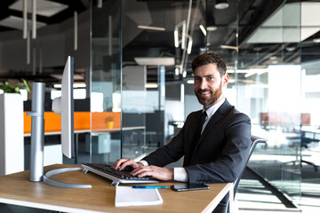Fototapeta premium Successful businesswoman looking at camera and smiling happy boss working at computer in modern office