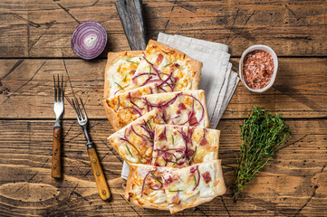 Flammkuchen or tarte flambee with cream cheese, bacon and onions. Wooden background. Top view