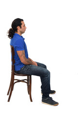 side view of man with ponytail and casual clothing  sitting a chair on white background