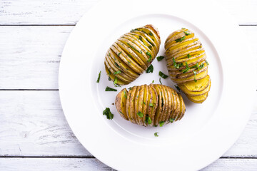 Baked potatoes on on a white plate on white wooden table