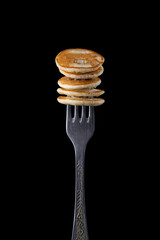 Tiny pancake on a fork on a dark background