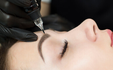 Permanent makeup. Permanent eyebrow tattoo. Cosmetologist applying permanent makeup on eyebrows -...