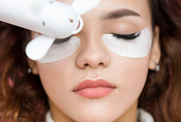 Eyelash extensions. a young woman undergoes a close-up eyelash extension procedure. The master dries the eyelashes after the procedure with a fan.