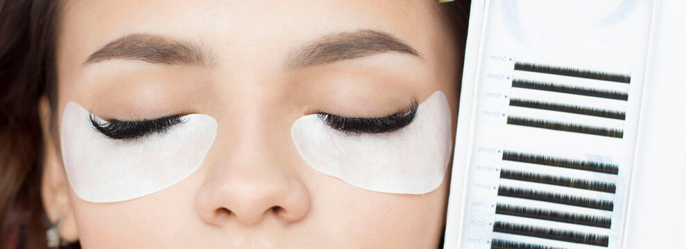 Eyelash extensions. Artificial eyelashes. The girl in the salon is doing an eyelash extension procedure. Close-up.