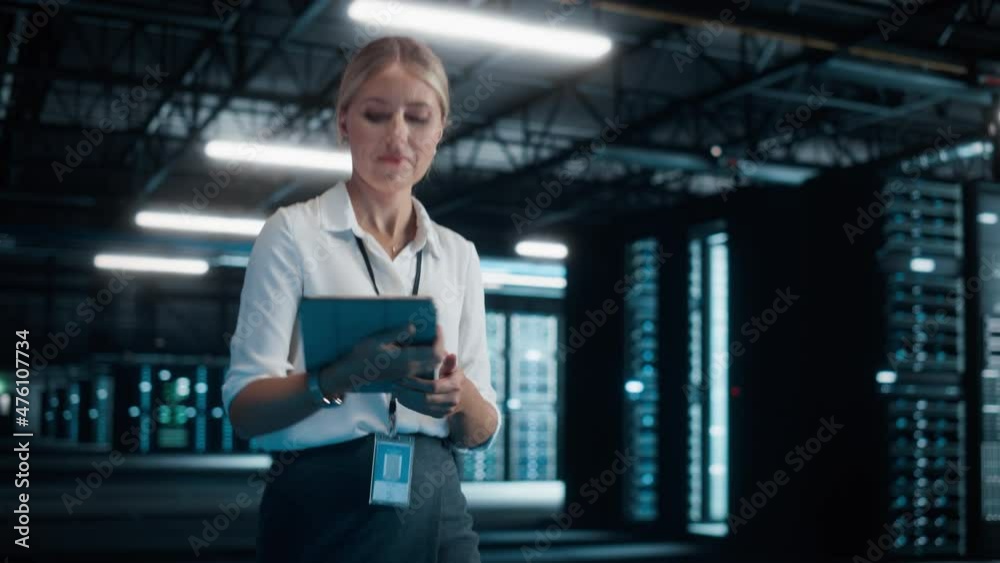 Poster successful female it specialist using tablet computer, walking through big warehouse data center. co