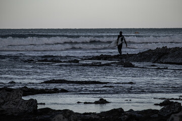 Haciendo surf en la playa de Sopelana, en Bizkaia, con el peñon de fondo.