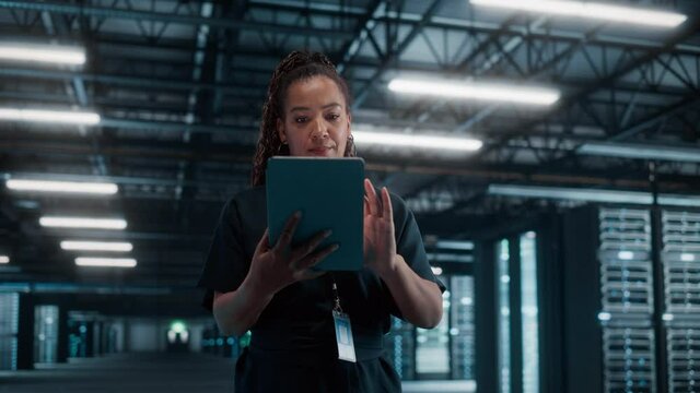 African American Female IT Specialist Using Laptop Computer, Standing in Big Warehouse Data Center. System Administrator working with SAAS, Cloud Web Services. e-Business Digital Entrepreneur - Powered by Adobe