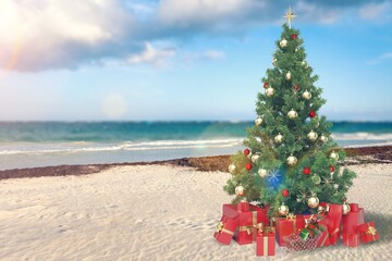 Christmas tree on the beach. Gift Boxes on sand beach shore. Decorated pine or fir tree.