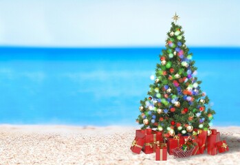 Christmas tree on the beach. Gift Boxes on sand beach shore. Decorated pine or fir tree.