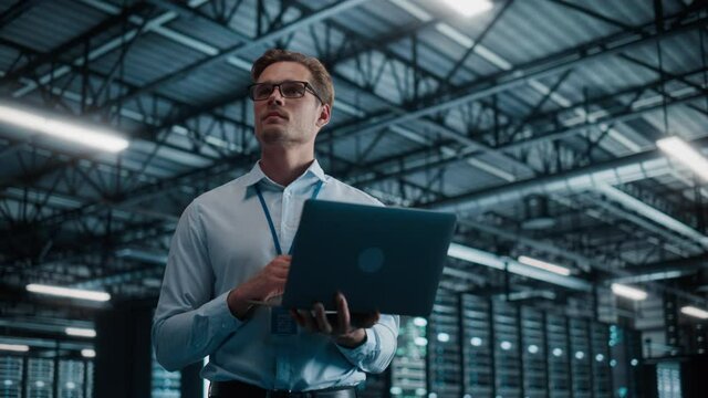 Big Data Center Chief Technology Officer Using Laptop Computer. Server Farm Cloud Computing Facility with System Administrator Working. Software as Solution and Cloud Computing with Cyber Security