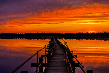 old iron footbridge on the lake at sunset