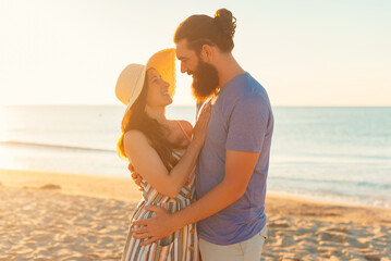 Young couple hug and enjoy life together at the beach during the summer and the sunset in backlight