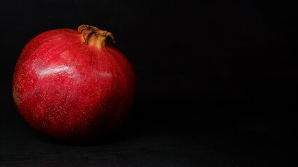 Fototapeta na wymiar red big pomegranate on dark background