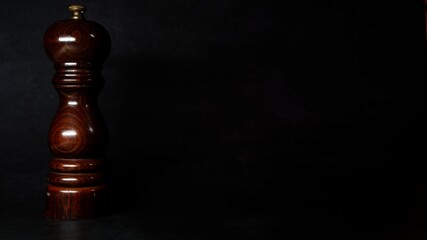 Brown pepper mill on dark background