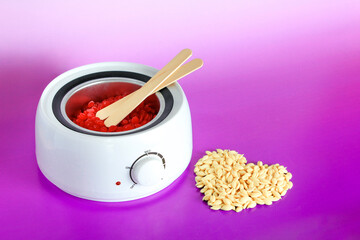Electric wax heater, wax granules and wooden spatulas. beauty industry, body care, beauty business