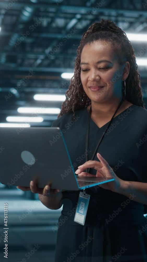 Poster Vertical Screen. Portrait of Black Female IT Specialist Using Laptop, Standing in Data Center. System Administrator Works on Web Services. Cloud Computing, Server Analytics, Cyber Security