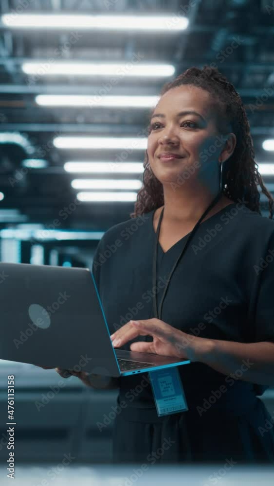 Poster Vertical Screen. Portrait of Black Female IT Specialist Using Laptop, Standing in Data Center. System Administrator Works on Web Services. Cloud Computing, Server Analytics, Cyber Security