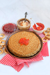 pancakes on plate, red caviar, jam, bread bagels on table. Maslenitsa holiday, pancakes week. traditional slavic festival meal.