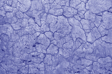 Cracked concrete old wall covered with beige cement surface as background. Old wall with cracks texture. Trendy color of the year 2022 . Ultra Violet creative and moody color of the picture