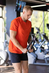 attractive strong handsome athlete man pumping up muscles in simulator in gym. muscle guy workout....